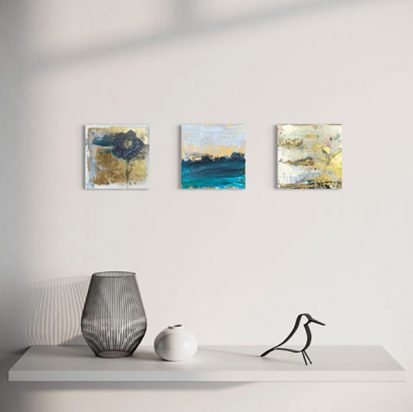 3 paintings in blue, white and gold hanging on a white wall